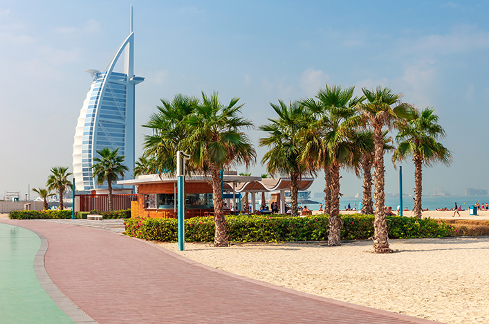 Palm trees and sand in front of the Burj al Arab building in Dubai