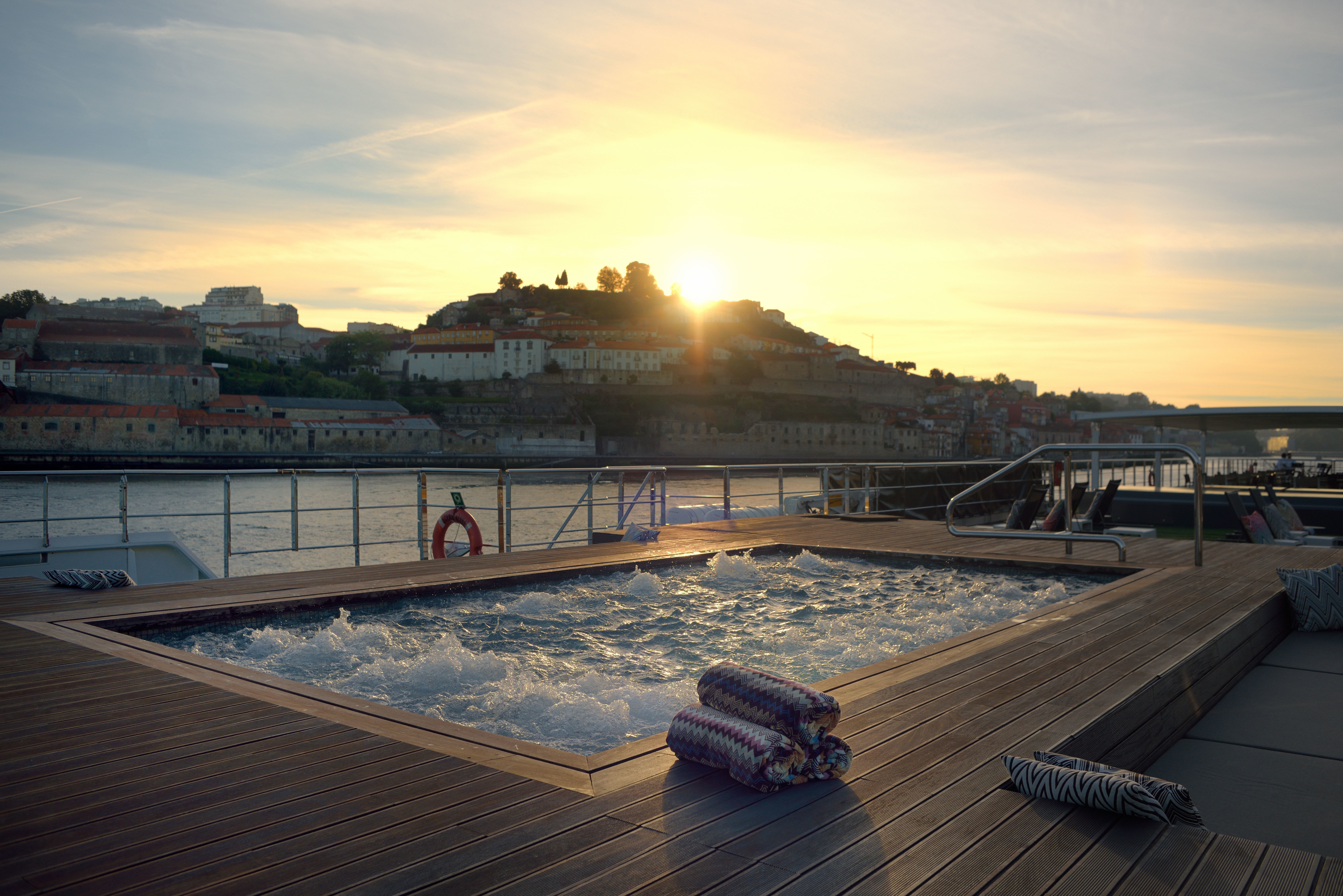 An outdoor pool located on the sun-drenched top deck of the Scenic Azure cruise ship, providing a view of the Douro River in Portugal. 