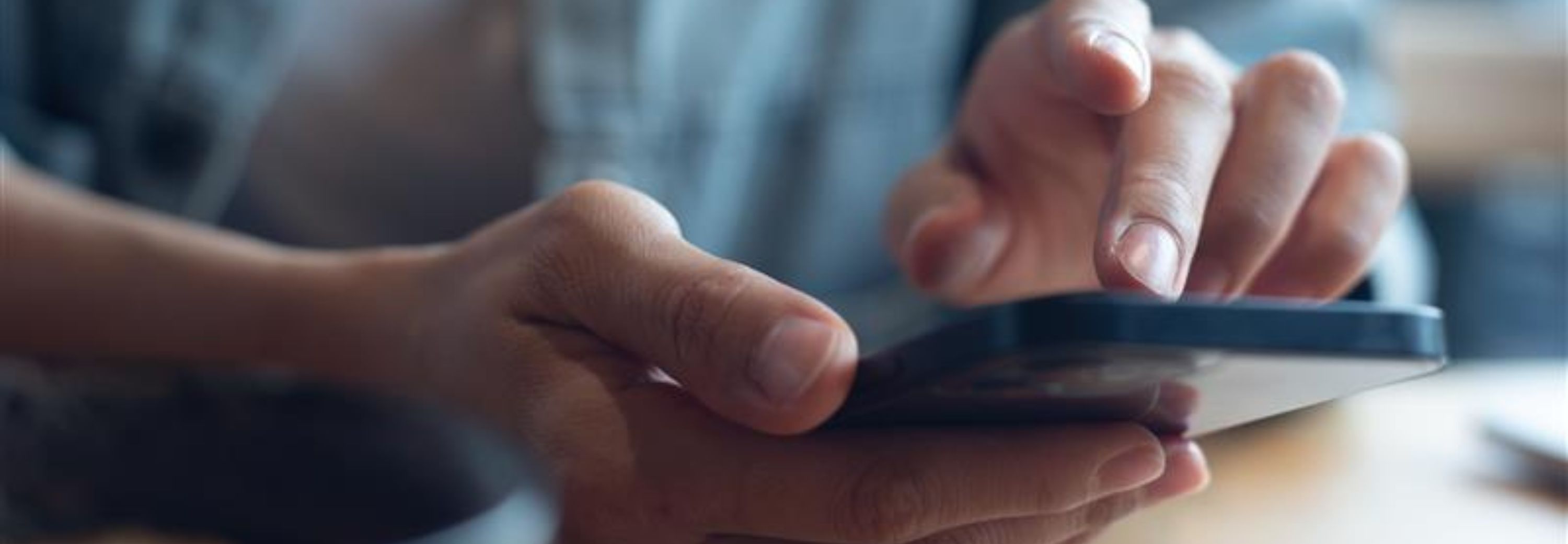 Close up of, woman sitting at wooden table using mobile phone in coffee shop