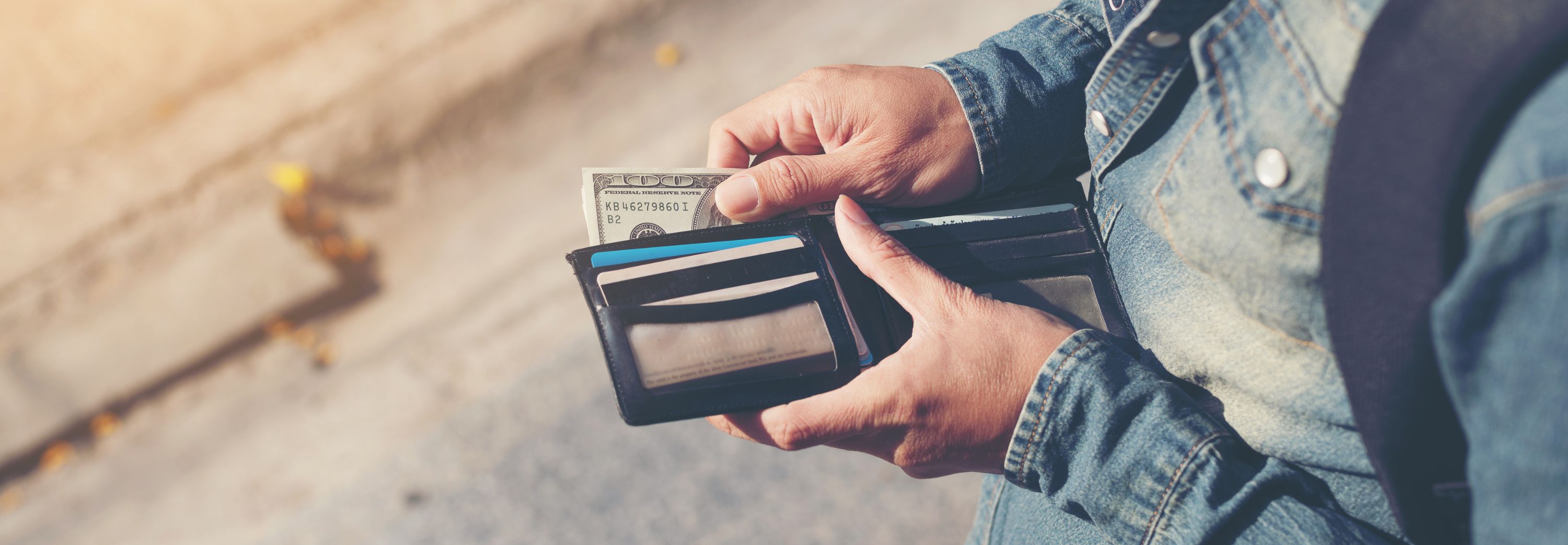 Man hands holding wallet with credit cards and stack of money.
