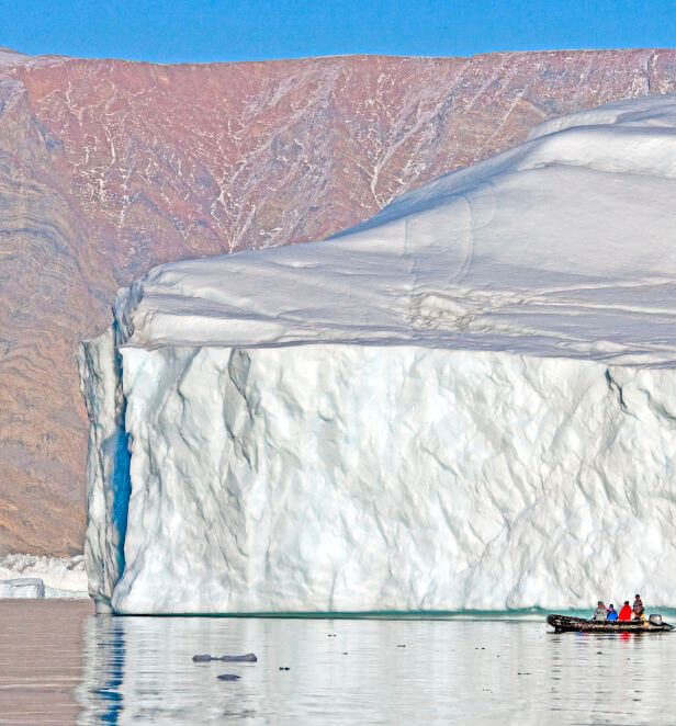 Zodiac boat near iceberg in Scoresbysund, Greenland