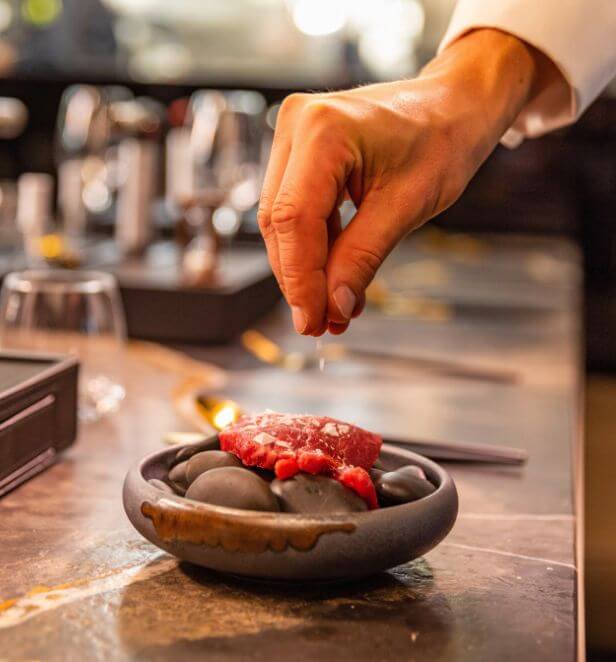 Chef seasoning a gourmet dish at Chef's Table on Scenic Eclipse