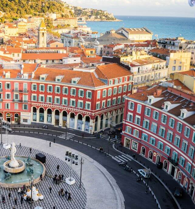 Fountain and red buildings in the main square of Nice, France