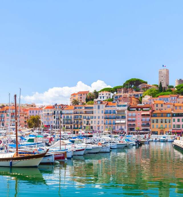 Boats docked at the marina with colorful buildings in Cannes, France