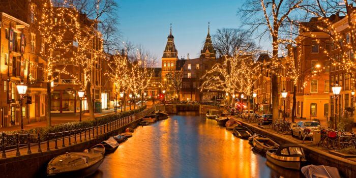 Twinkling Christmas lights along a canal in Amsterdam, Netherlands during the evening