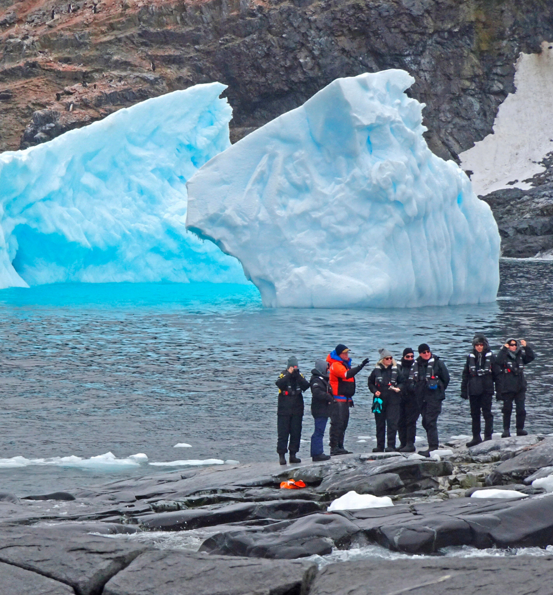 Tour group viewing blue coloured ice bergs on sea water