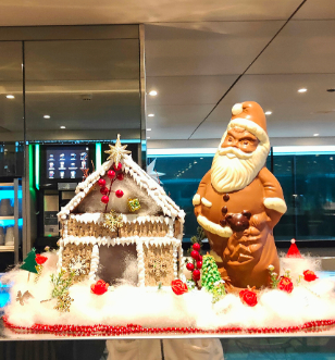 Gingerbread house and chocolate santa in a glass display